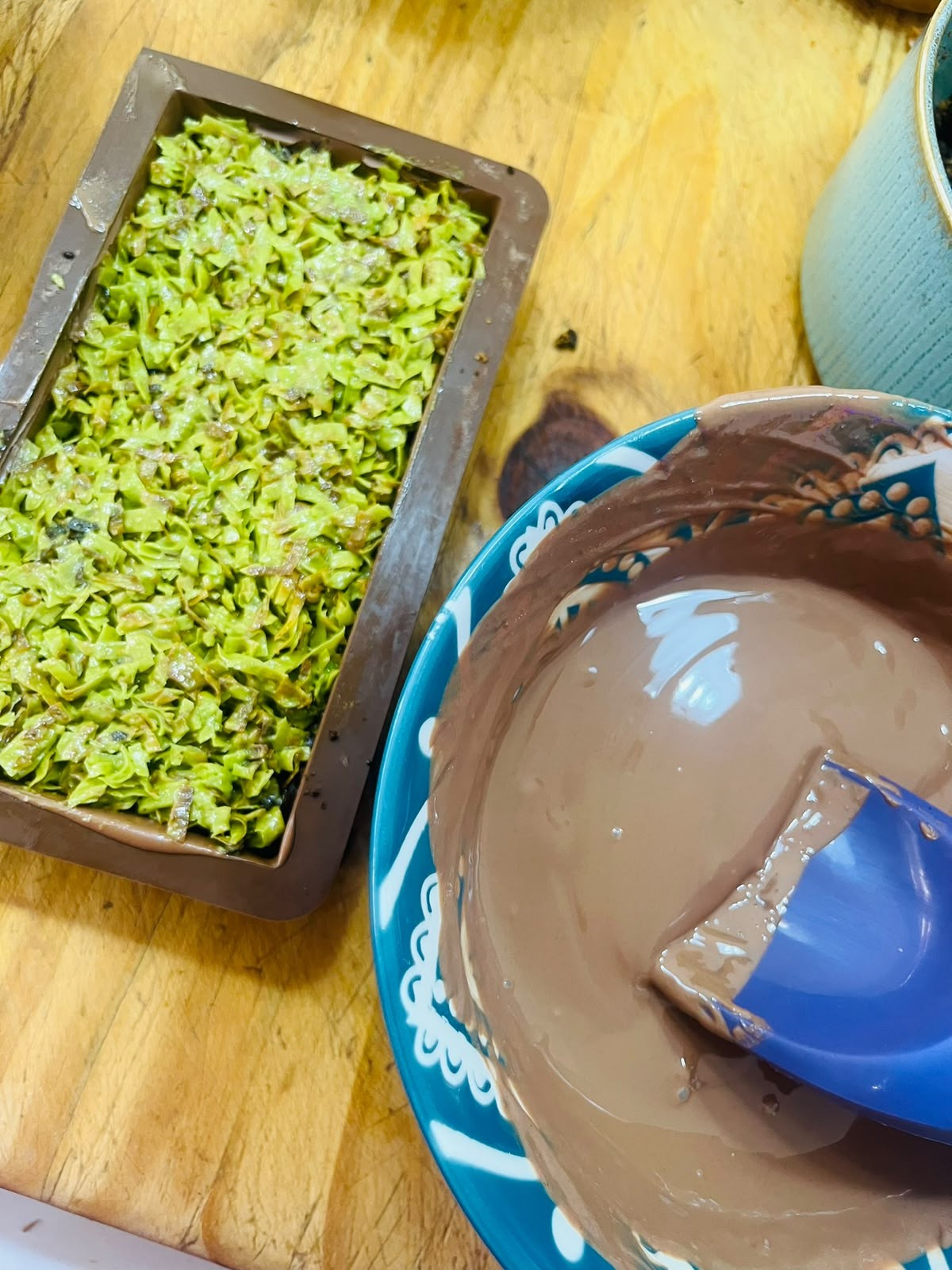 Pistachio filling in the mould beside a bowl of melted Belgian chocolate